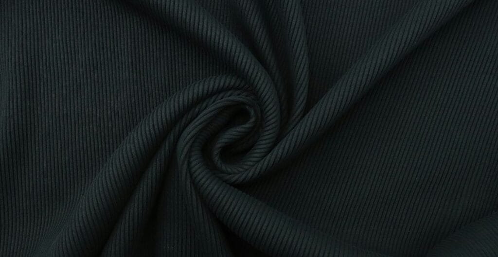 Close-up of dark ribbed fabric twisted into a spiral pattern.