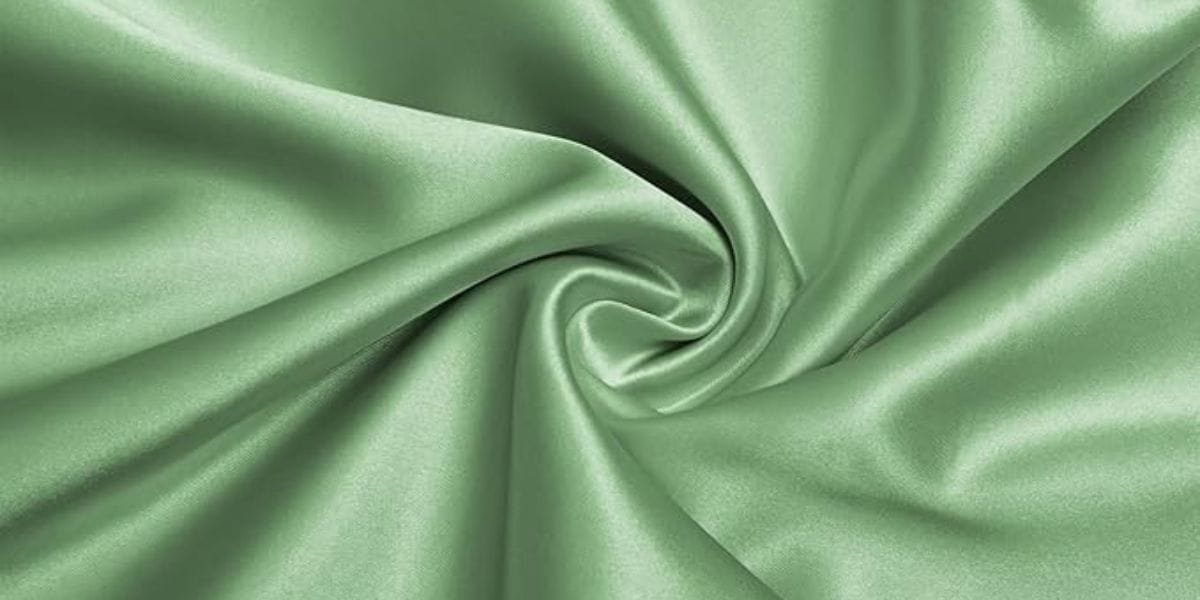 Light green satin fabric with a smooth, shiny surface twisted into a swirl pattern.