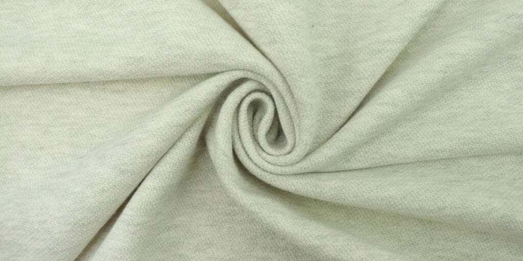 Light grey heathered knit fabric twisted into a spiral.