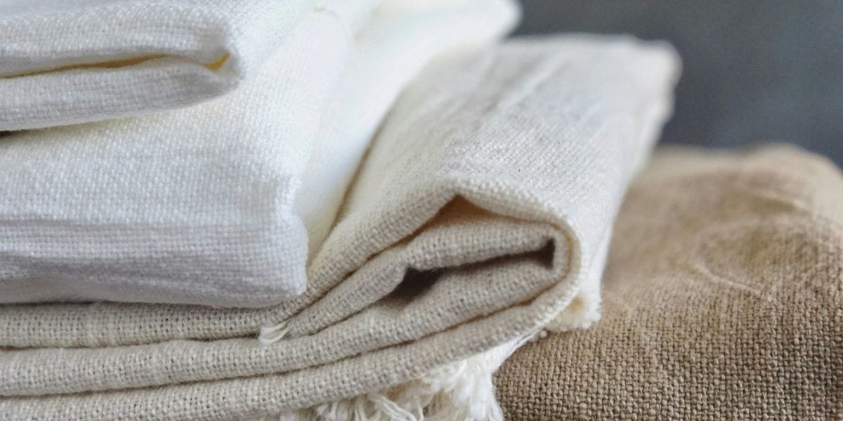 Stack of folded natural linen fabrics in neutral tones