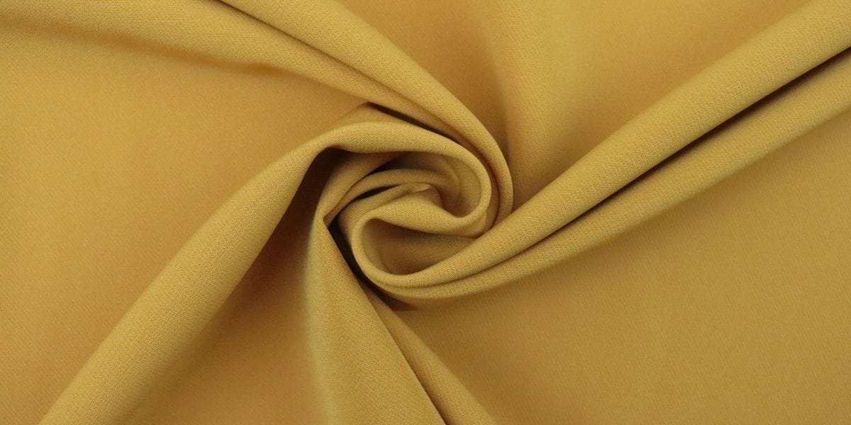 Close-up of mustard yellow fabric twisted into a swirl pattern.
