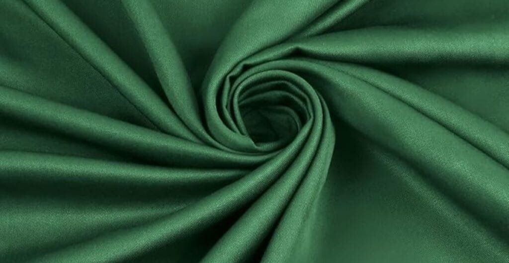 Close-up of emerald green satin fabric twisted into a swirl pattern