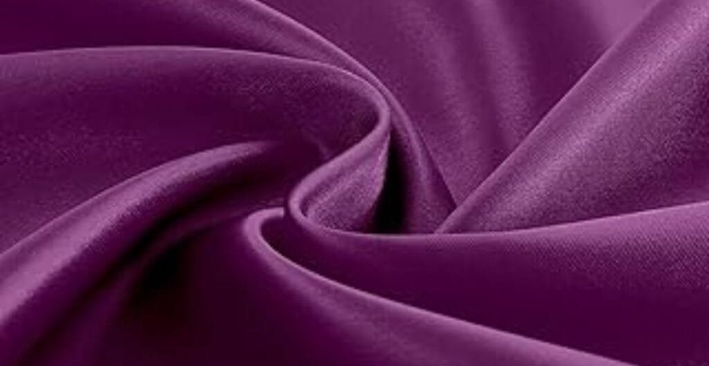Close-up of smooth, shiny purple satin fabric with elegant folds.