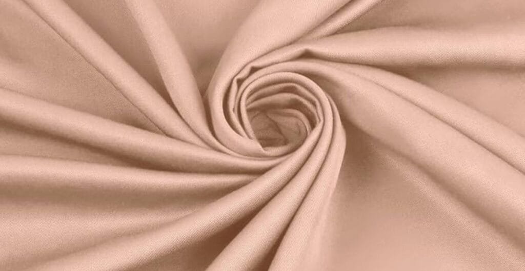 Close-up of beige fabric with a soft, smooth texture, swirled into a spiral shape.