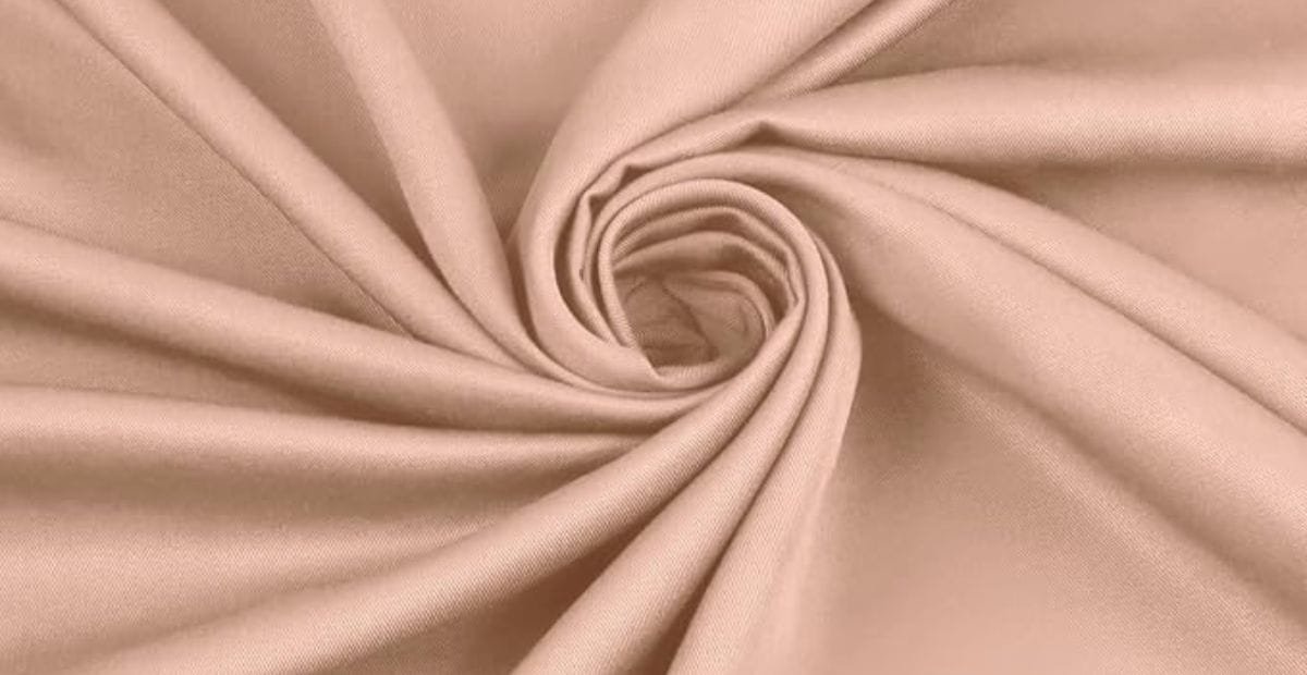 Close-up of beige fabric with a soft, smooth texture, swirled into a spiral shape.