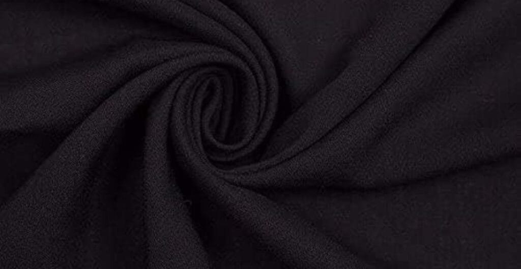 Close-up of black fabric with a soft, slightly textured surface, twisted into a spiral pattern.
