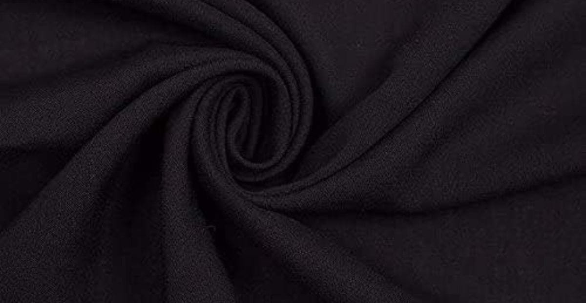 Close-up of black fabric with a soft, slightly textured surface, twisted into a spiral pattern.