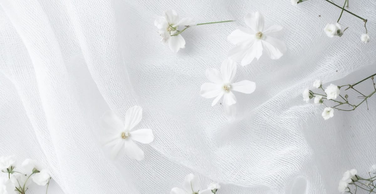 White fabric with scattered white flowers and small white buds.