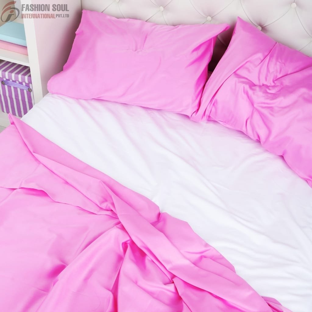 A bed with pink satin pillowcases and a pink satin bedsheet, partially pulled back to reveal a white sheet underneath. There is a bit of a nightstand with a striped gift box in the background.