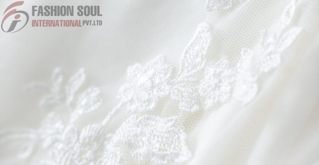 Close-up of delicate white linen fabric with floral embroidery by Fashion Soul International Pvt. Ltd.