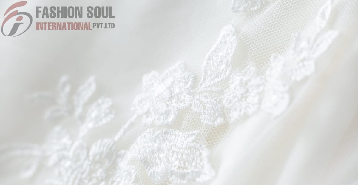 Close-up of delicate white linen fabric with floral embroidery by Fashion Soul International Pvt. Ltd.