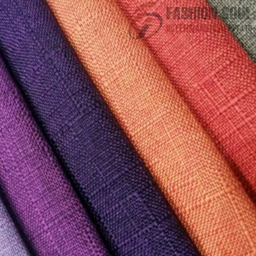 Close-up of rolled fabrics in various colors, including purple, dark blue, orange, red, and grey, arranged side by side. The fabric texture is visibly woven.
