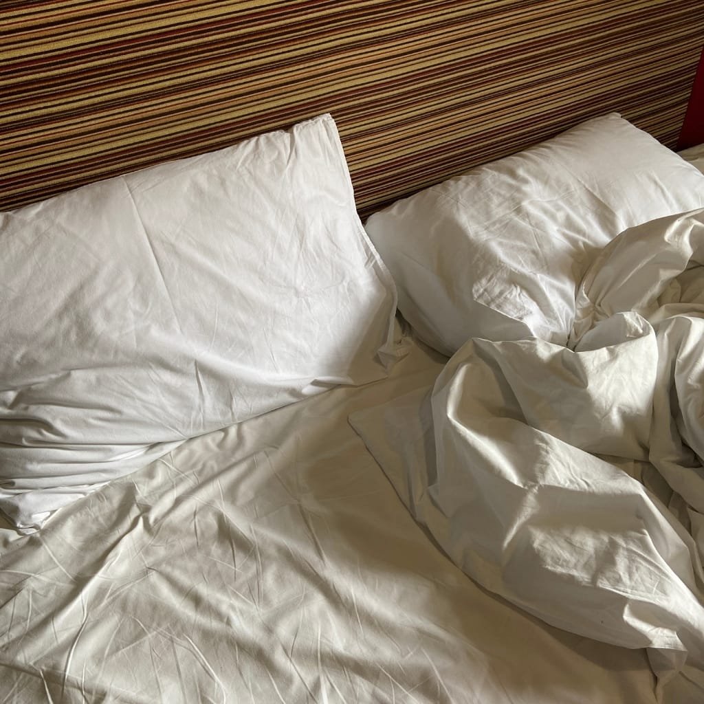 A close-up of a white bed with crumpled bedsheets and an open book resting on it. There is a logo in the top right corner that reads "Fashion Soul International Pvt. Ltd."