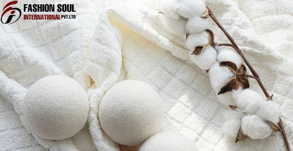 Close-up of three white, textured bath bombs on a soft, white cloth with a cotton branch in the background.