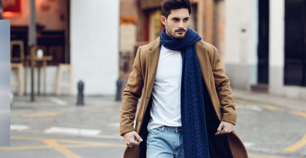 A man wearing a brown sport coat with a dark blue scarf draped around his neck.