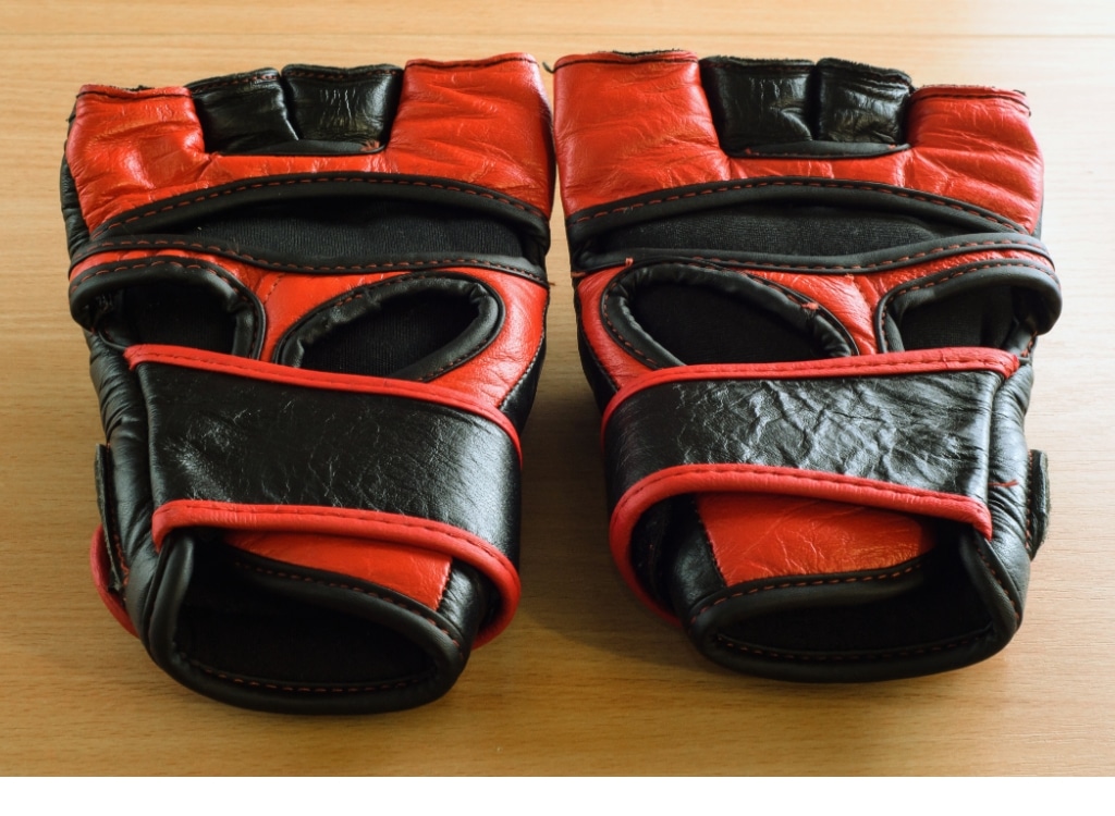 Pair of black and red MMA gloves resting on a wooden surface.