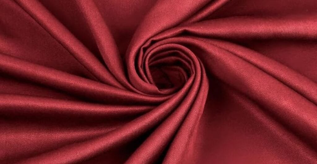 Close-up of red satin fabric arranged in a spiral pattern.