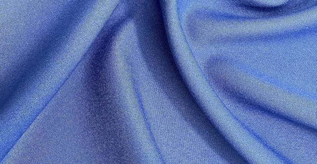 Smooth blue satin fabric with soft folds and a glossy finish.