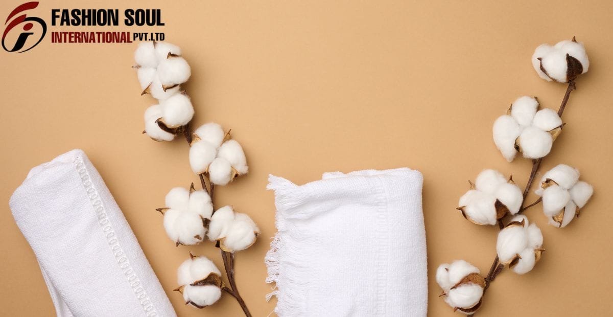 Close-up image of white cotton pads, white folded towels, and cotton plant branches with fluffy white cotton bolls against a beige background, with the "Fashion Soul International Pvt. Ltd" logo in the top left corner.