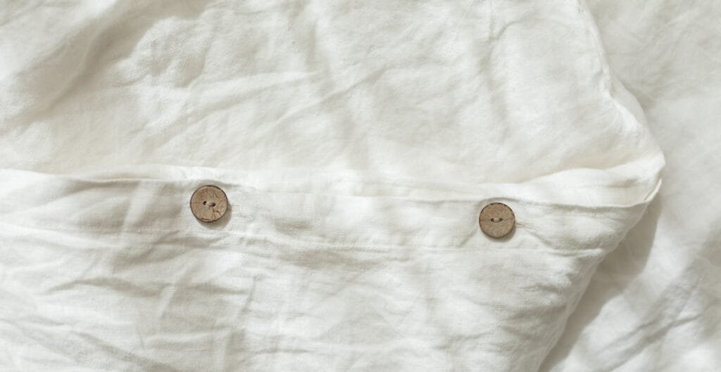 A close-up of a white fabric shirt with two small wooden buttons sewn onto it.