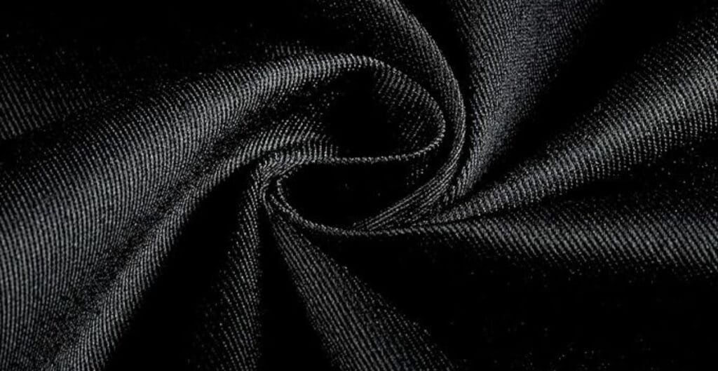 Close-up of black satin fabric twisted into a swirl, showing its smooth texture and subtle sheen.