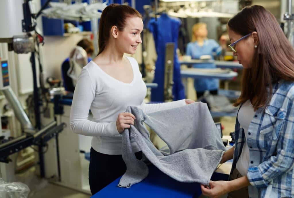 A woman wearing modern, eco-friendly workwear made from sustainable materials, standing confidently in a production facility surrounded by environmentally friendly manufacturing processes.