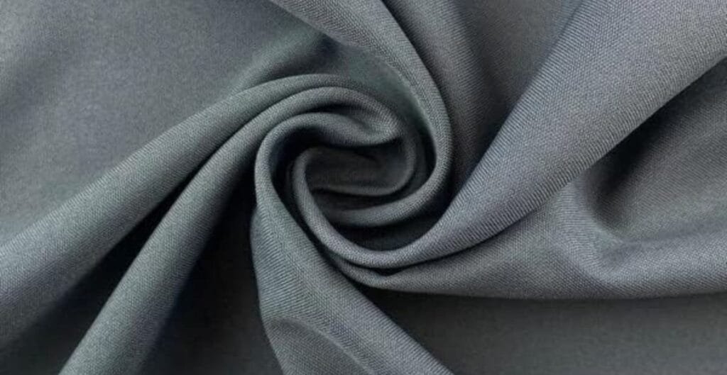Close-up of smooth, dark grey fabric swirled into a spiral pattern.