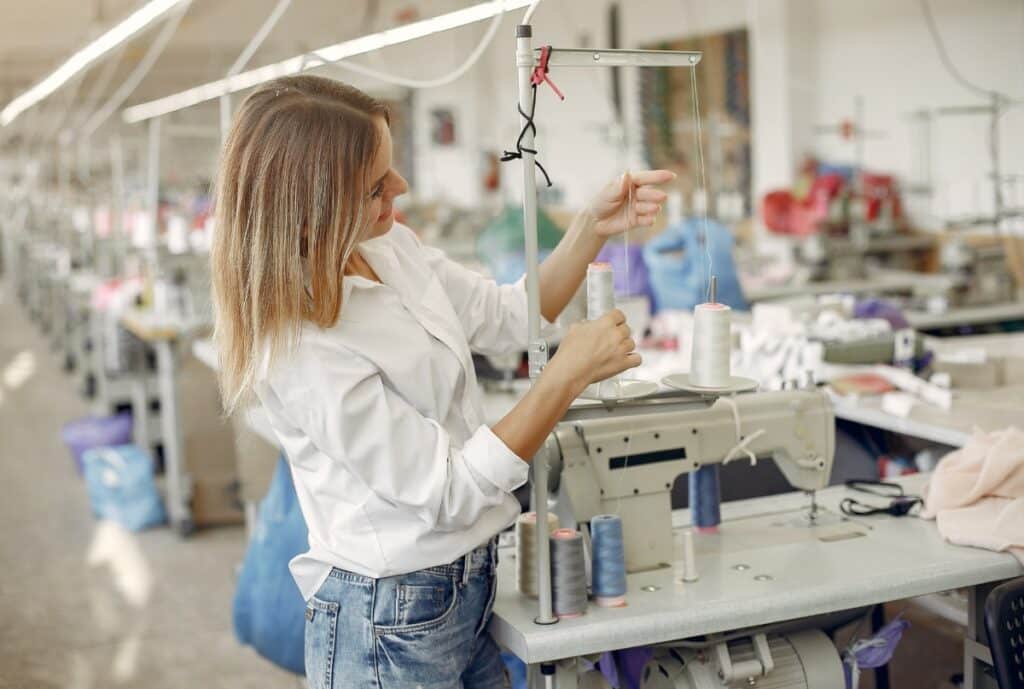 A factory worker wearing women workwear, including safety gear and professional attire, manufacturing garments in a production line.