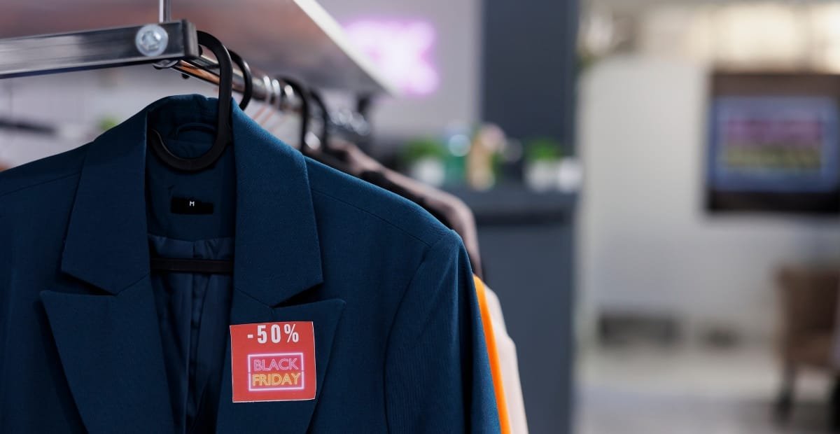 A dark blue blazer hanging on a rack with a red and yellow "Black Friday" sale tag showing a 50% discount.