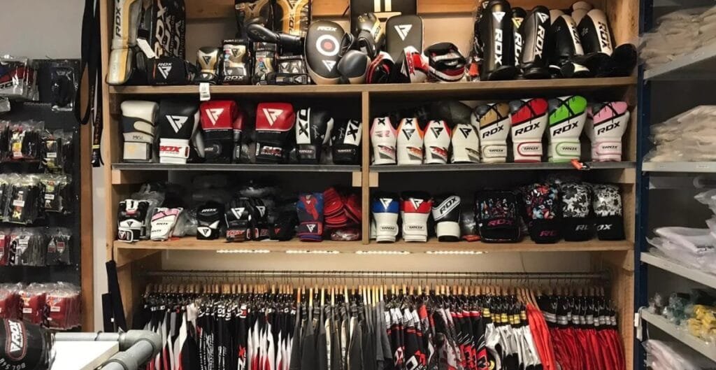 A procurement manager evaluating MMA gear from multiple suppliers, with comparison charts and product samples laid out on a table.