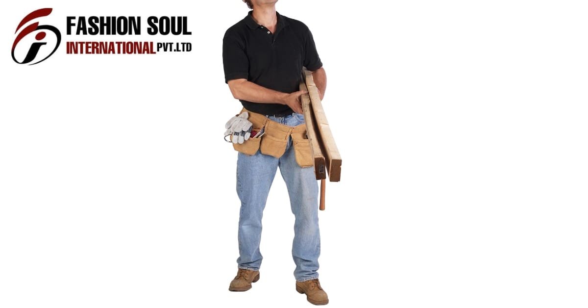 Worker wearing a black polo shirt and blue jeans, holding lumber with a tool belt full of tools around the waist, standing against a white background."