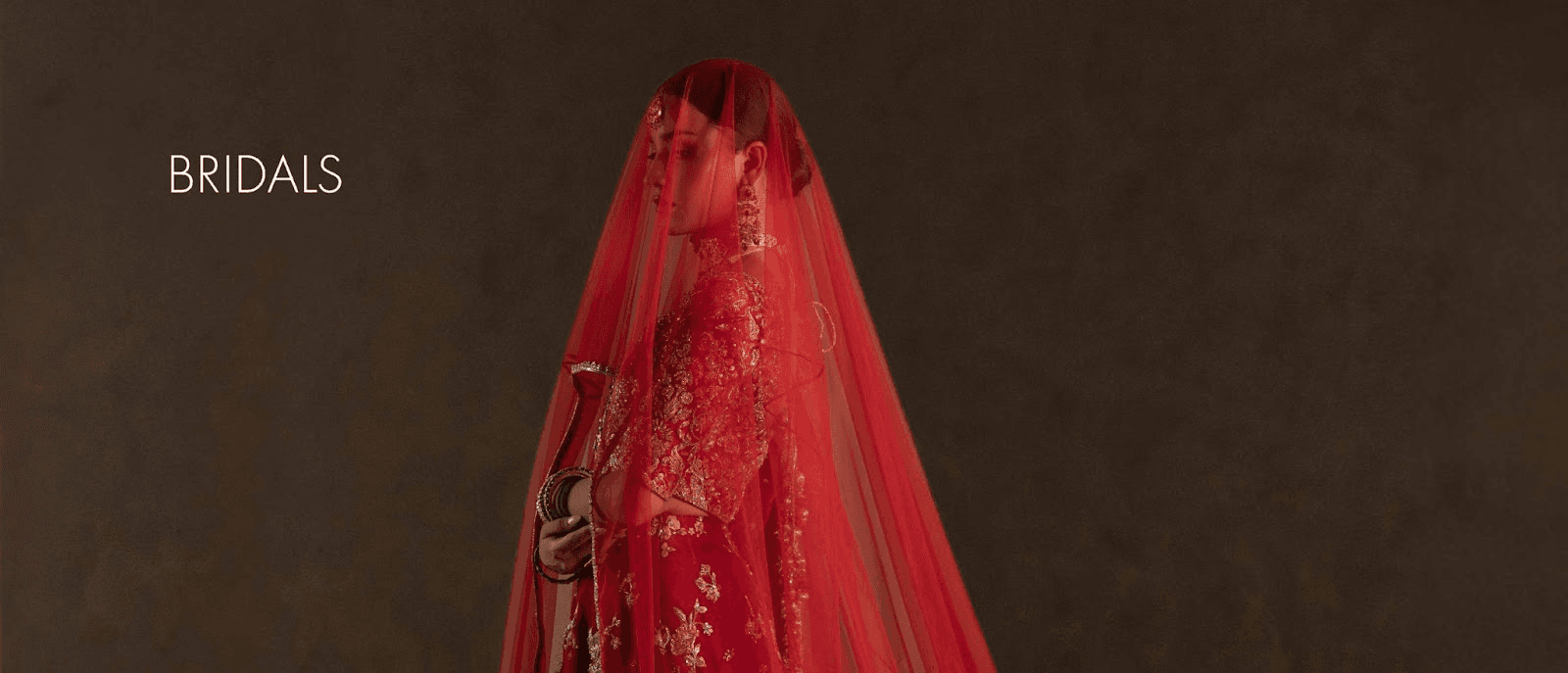 A person wearing a bright red veil or garment against a dark background, with the word “NOKA” or label in white on the left.