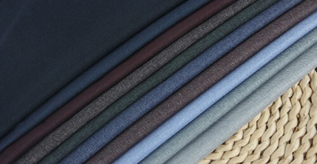 A close-up of three fabric swatches: one showing a lightweight, breathable knit with visible airy weave; one showcasing a smooth, moisture-wicking sports fabric with a slight sheen; and one featuring a breathable mesh panel. The swatches are arranged in a row with a generic clothing label and a soft, neutral background to convey comfort and everyday wear.