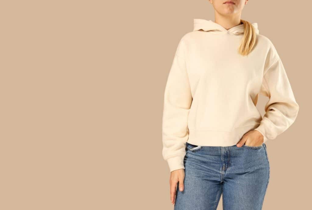 Factory workers and sewing machines in a modern Spain-based garment manufacturing facility producing oversized hoodies.