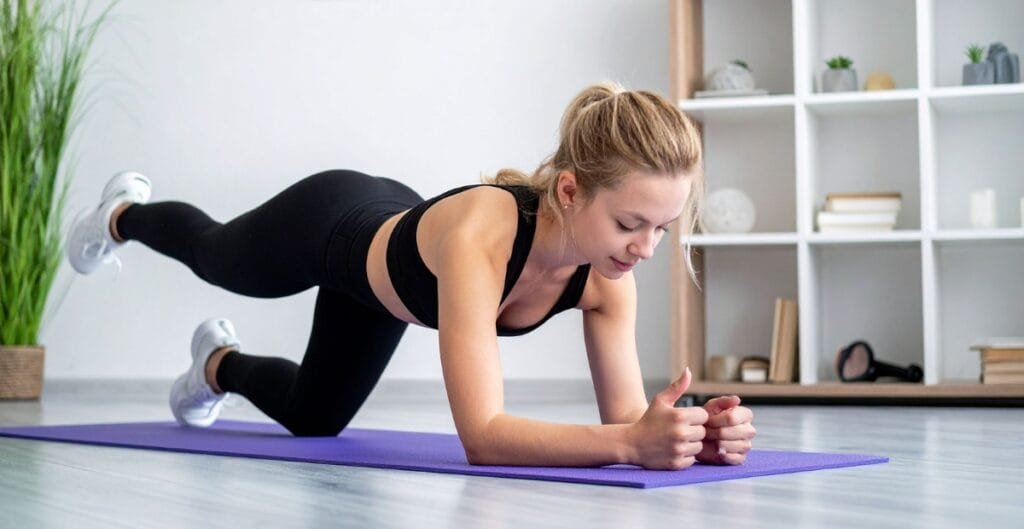 Woman in black exercise leggings performing a plank pose on a purple mat, strengthening her core