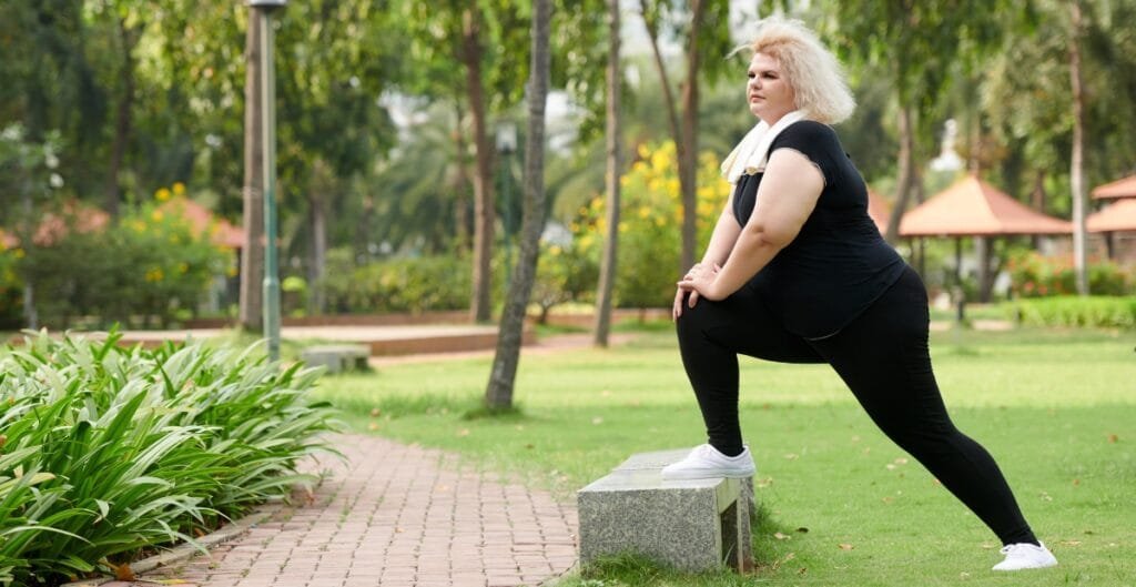 Curvy woman in leggings warming up in a park, demonstrating how plus-size activewear supports movement