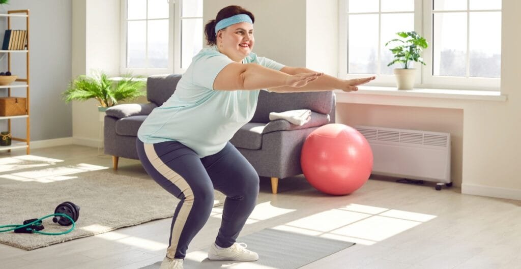 A plus-size woman doing squats at home in cute plus size leggings, perfect for exercise and comfort.