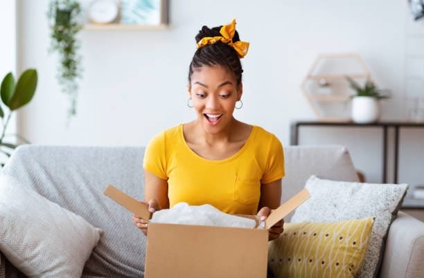Happy woman unboxing affordable fashion clothing from Boohoo and similar online shops”

