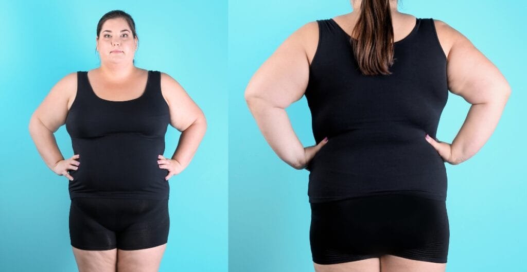 Woman in black tank top and plus size exercise shorts posing against a blue backdrop