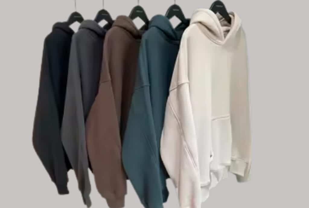 Wholesale order handoff of bundled hoodie boxes labeled for retailers, showing multiple packages ready for shipment and a calculator and notepad in the background.