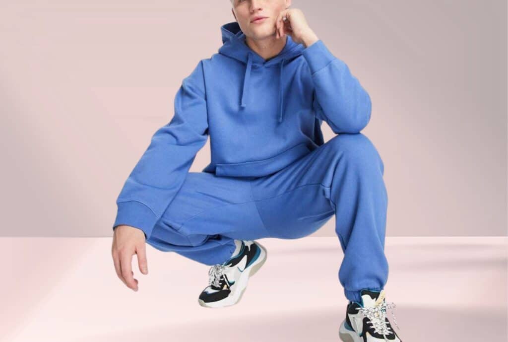 A diverse group of people trying on casual sweatsuits in a modern LA showroom, with racks of apparel in the background.