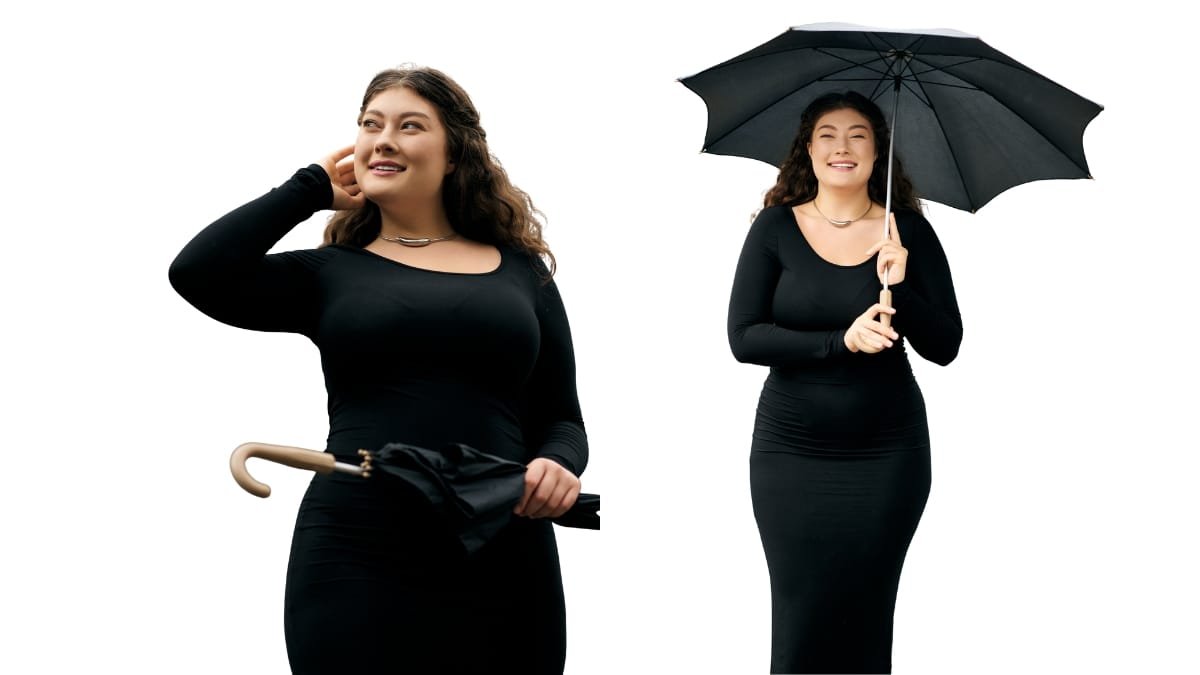 A confident plus-size woman wearing a black dress, holding an umbrella with a black canopy, smiling at the camera.