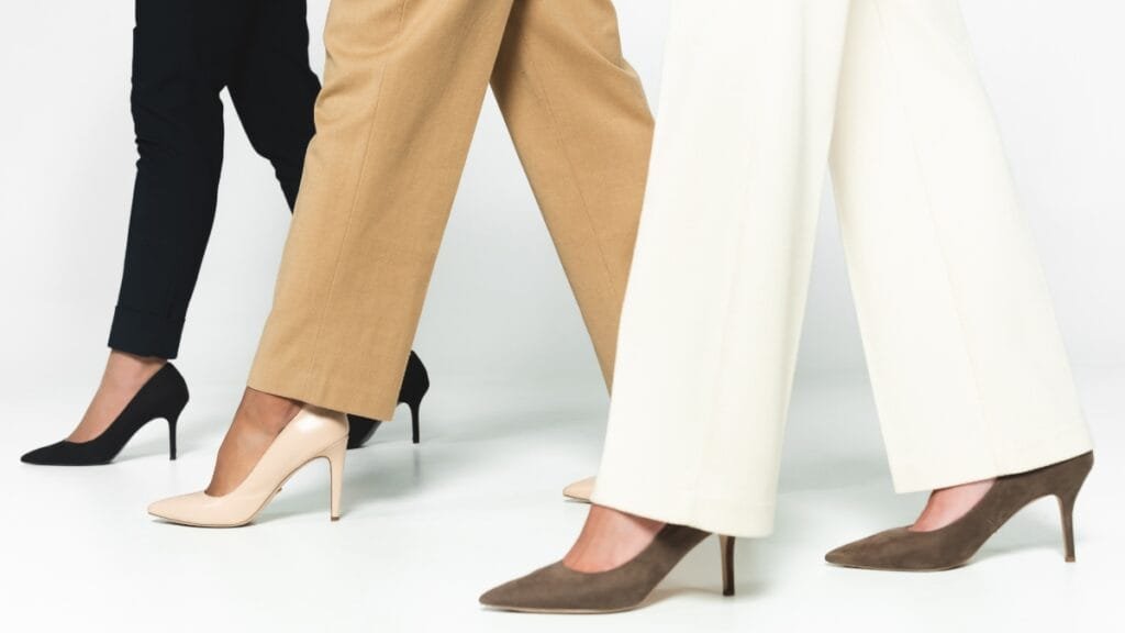 A stylish woman wears dressy pants in beige, black, and white paired with elegant high heels, showcasing a chic and professional look