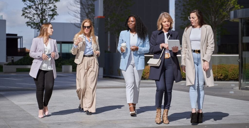 Women walking outdoors in stylish female formal pants and blazers.