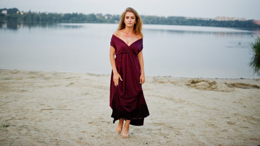 Woman in a mauve velvet dress standing by the water