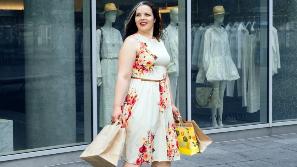 plus floral dress in a light floral print worn outdoors in a modern shopping street setting