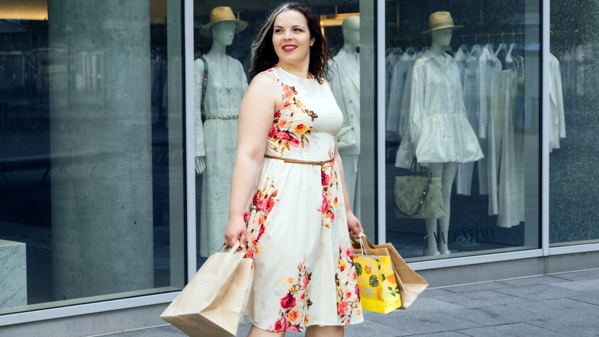 plus floral dress in a light floral print worn outdoors in a modern shopping street setting