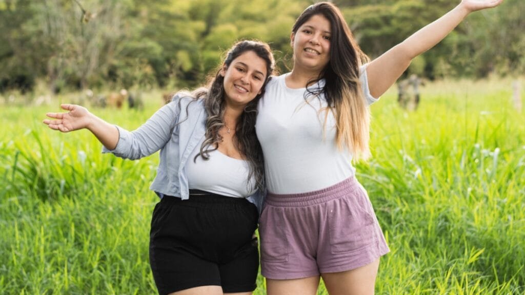 Two plus-size women smiling and posing in comfortable shorts in a grassy field