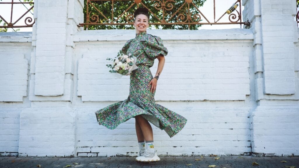 Woman wearing a flowy size 12 dress while walking outdoors in front of a white wall