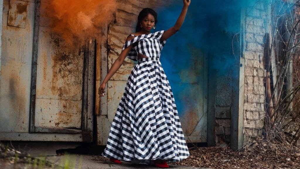 A woman posing in a dramatic black and white tiered dress midi against a colorful artistic background